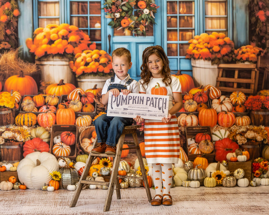 A little girl and a little boy hold a pumpkin farm signs in front of a large group of pumpkins in Warwick NY